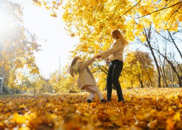 Portrait of happy mother and daughter in autumn forest at sunset. Autumn women.