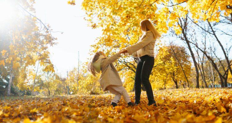 Portrait of happy mother and daughter in autumn forest at sunset. Autumn women.